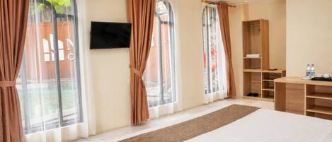 Una habitación de hotel con una cama grande, un televisor montado en la pared y un armario.