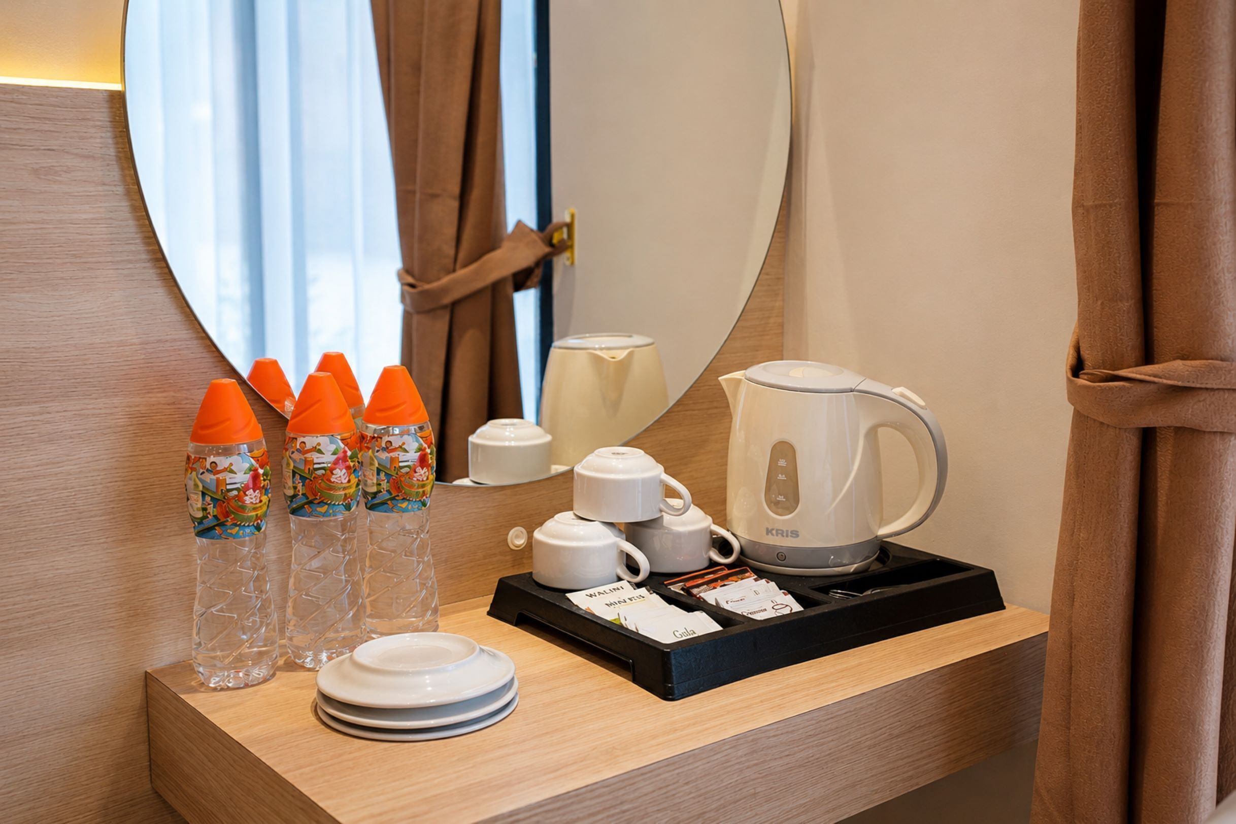 Una habitación de hotel con una mesita de noche de madera que incluye una cafetera, teteras, tazas y una bandeja con un cápsula de café Starbucks.