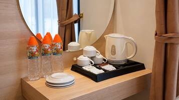 Una habitación de hotel con una mesita de noche de madera que incluye una cafetera, teteras, tazas y una bandeja con un cápsula de café Starbucks.