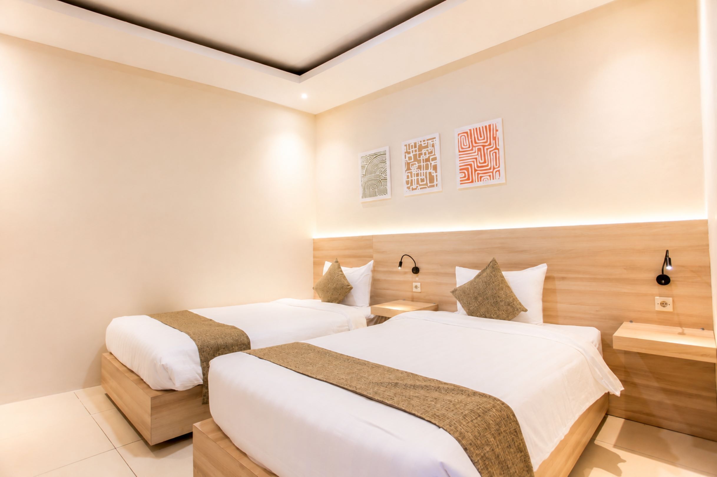 Een hotelkamer met twee bedden, een houten hoofdeinde, nachtkastjes en wanddecoratie.