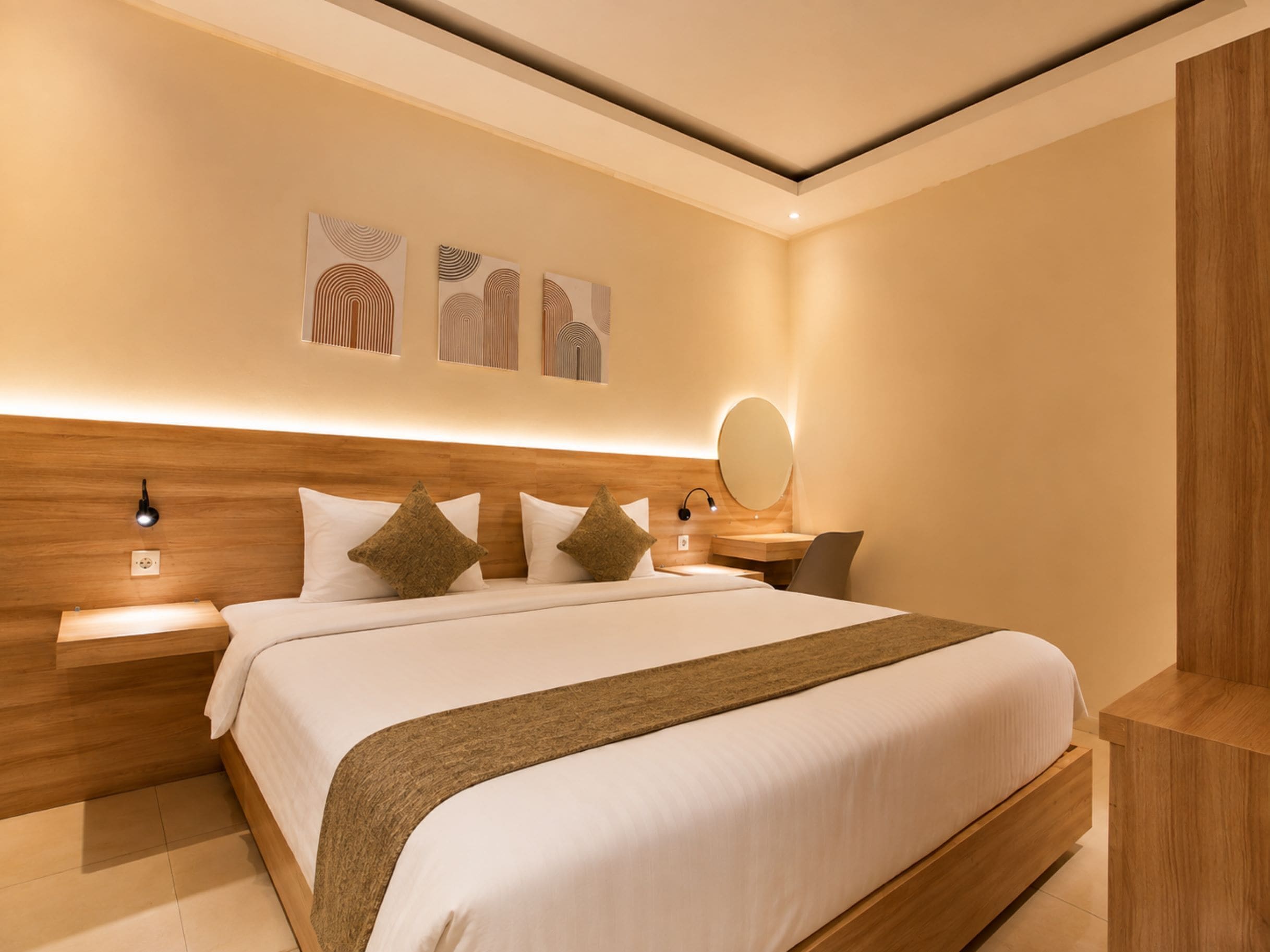 A modern hotel room with a large bed, wooden headboard, bedside tables, and wall-mounted artwork.