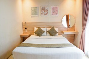 A neatly made bed with pillows, a bedside table, a wall-mounted mirror, and three framed wall art pieces.