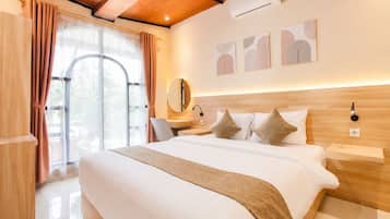 Habitación de hotel con una cama grande, cabecero de madera, un escritorio con silla, un espejo y obras de arte en la pared.