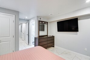 Ein Schlafzimmer mit einem Bett, einem Schminktisch, einem Spiegel und einem an der Wand befestigten Fernseher.