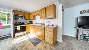 Eine Küche mit Holzschränken, einer Mikrowelle, einem Backofen und einem Fernseher.