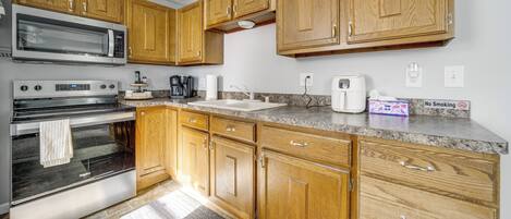 A kitchen with wooden cabinets, stainless steel appliances, granite countertops, and a 'No Smoking' sign.