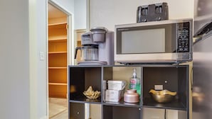 A kitchenette with a coffee maker, microwave, and shelves with decorative items. - Convenient High Desert Stay Near Route 66 (Victorville)