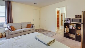 A bedroom with a bed, a sofa, a coffee machine, a TV, and a bookshelf. - Convenient High Desert Stay Near Route 66 (Victorville)