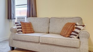 A light-colored sofa with two striped pillows, positioned near a window with curtains. - Convenient High Desert Stay Near Route 66 (Victorville)