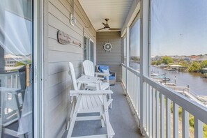 A balcony with white Adirondack chairs, a small table, and a view of a water body with docks. - Waterfront Condo w/ Views & Pool in Little River (Little River)