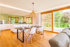 Eine moderne Küche mit Essbereich, großen Fenstern und Blick ins Grüne.