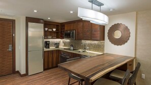 Uma cozinha moderna com armários de madeira, eletrodomésticos de aço inoxidável, uma ilha grande e um elemento decorativo original na parede.