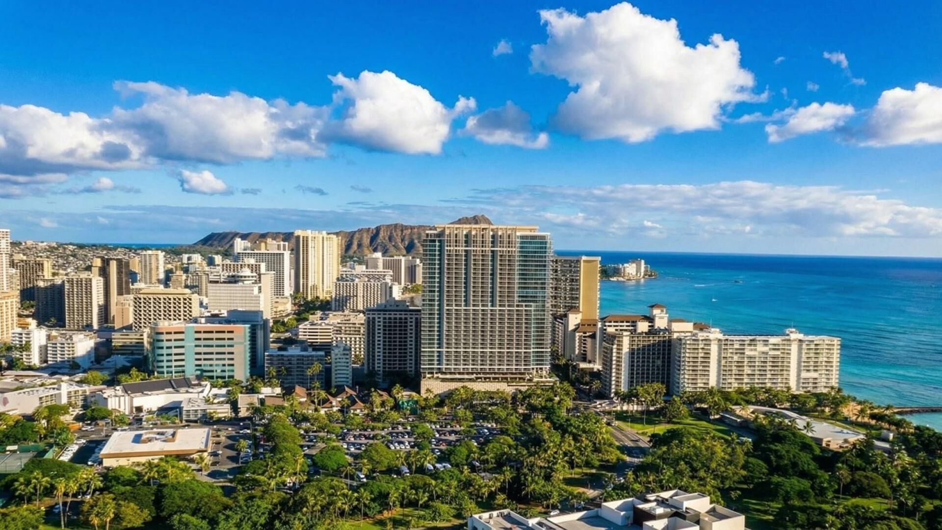 Un paysage urbain côtier avec de hauts immeubles, un ciel bleu dégagé et une vue sur l’océan.