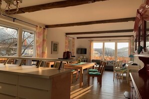 A spacious kitchen with a large island, wooden beams, and a view through large windows. - Holiday apartment with 1 bedroom (Garmisch-Partenkirchen)