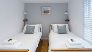 A twin room with two beds, a framed picture on the wall, and a window with blinds. - Pickwick's Place - UK51958 (Broadstairs)