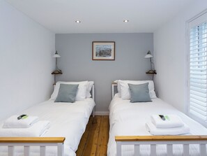 Ein Doppelzimmer mit zwei Betten, einem gerahmten Bild an der Wand und einem Fenster mit Jalousien.