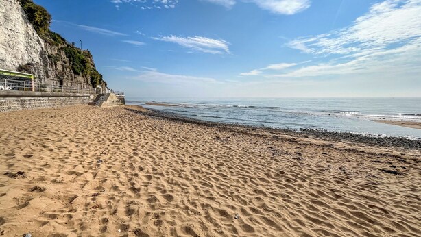 A sandy beach with a rocky cliff and a staircase leading up. - Pickwick's Place - UK51958 (Broadstairs)