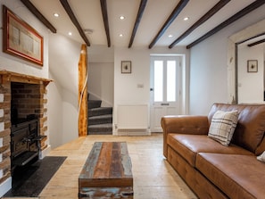 Ein Wohnzimmer mit Kamin, einem braunen Ledersofa, einem Holztisch und einer Treppe zu einem anderen Raum.