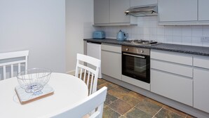 A modern kitchen with white cabinets, a gas stove, a dishwasher, and a blue kettle. - Pickwick's Place - UK51958 (Broadstairs)