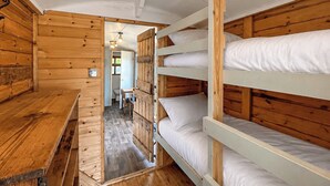 A wooden cabin with bunk beds, a wooden table, and a small bathroom visible through an open door. - Ewe - Nice - UK51949 (Sutton on Sea, near Mablethorpe)