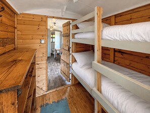 A wooden cabin with bunk beds, a wooden table, and a small bathroom visible through an open door. - Ewe - Nice - UK51949 (Sutton on Sea, near Mablethorpe)