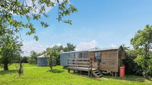 A rustic wooden cabin with a wooden deck and a metal shed in a grassy field. - Ewe - Nice - UK51949 (Sutton on Sea, near Mablethorpe)