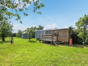 A rustic wooden cabin with a wooden deck and a metal shed in a grassy field. - Ewe - Nice - UK51949 (Sutton on Sea, near Mablethorpe)