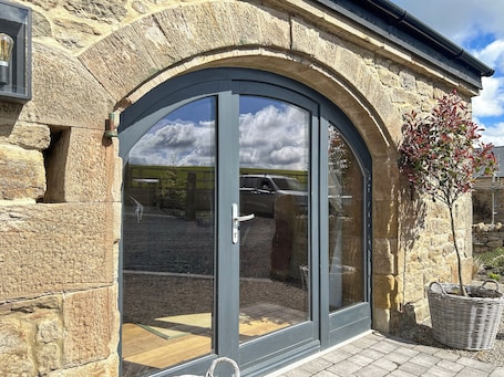 A stone building with a large arched glass door, a small tree, and a wicker basket.. 1 bedroom accommodation in Consett