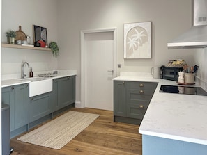 A kitchen with grey cabinets, a white countertop, a wooden floor, and a white door.