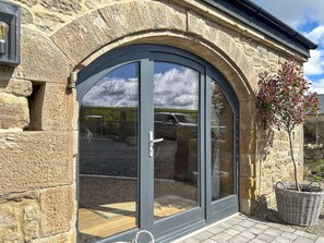 A stone building with a large arched glass door, a small tree, and a wicker basket. - 1 bedroom accommodation in Consett (Consett)