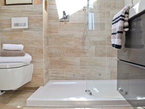 A modern bathroom with a bathtub, a shower, and a toilet. - 1 bedroom accommodation in Plymouth (Plymouth)