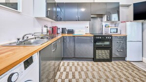 Une cuisine moderne dotée d’appareils électroménagers en acier inoxydable, d’un plan de travail en bois et d’un tapis à carreaux.
