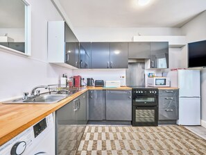 Eine moderne Küche mit Edelstahlgeräten, einer Holzarbeitsplatte und einem Schachbrettteppich.