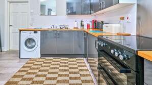 Une cuisine moderne équipée d’un lave-linge, d’appareils électroménagers en acier inoxydable et d’un tapis à carreaux.