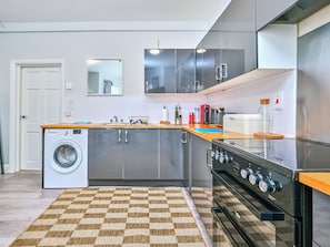 Eine moderne Küche mit Waschmaschine, Edelstahlgeräten und einem karierten Teppich.