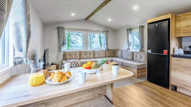 Een moderne keuken met een houten aanrecht, een zwarte koelkast en een zithoek met een bank.