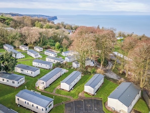A cluster of mobile homes with a private parking area, set against a backdrop of trees and a coastal view. - 3 bedroom accommodation in Bideford (Bideford)