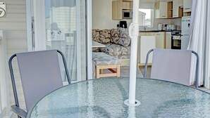 A compact living space with a glass table, two chairs, a sofa, and a kitchenette. - Hayling Island Retreat (Hayling Island)