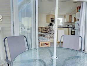 Ett kompakt vardagsrum med ett glasbord, två stolar, en soffa och ett litet kök.