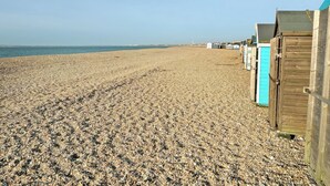 A pebbled beach with wooden beach huts and a clear sky. - Hayling Island Retreat (Hayling Island)