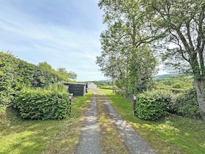 A rural road leading to a building with a small shed and a fence. - 2 bedroom accommodation in Brecon, Near Hay-on Wye (Brecon, Near Hay-on Wye)