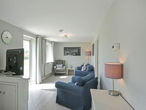 A modern living room with a sofa, a lamp, a TV, and a clock on the wall. - 2 bedroom accommodation in Brecon, Near Hay-on-Wye (Brecon, Near Hay-on Wye)