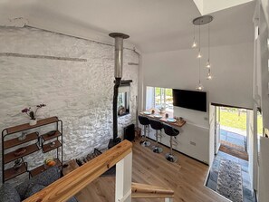Eine moderne Küche mit Steinwand, Holzbarhocker, einer Holzbank und einem an der Wand montierten Fernseher.