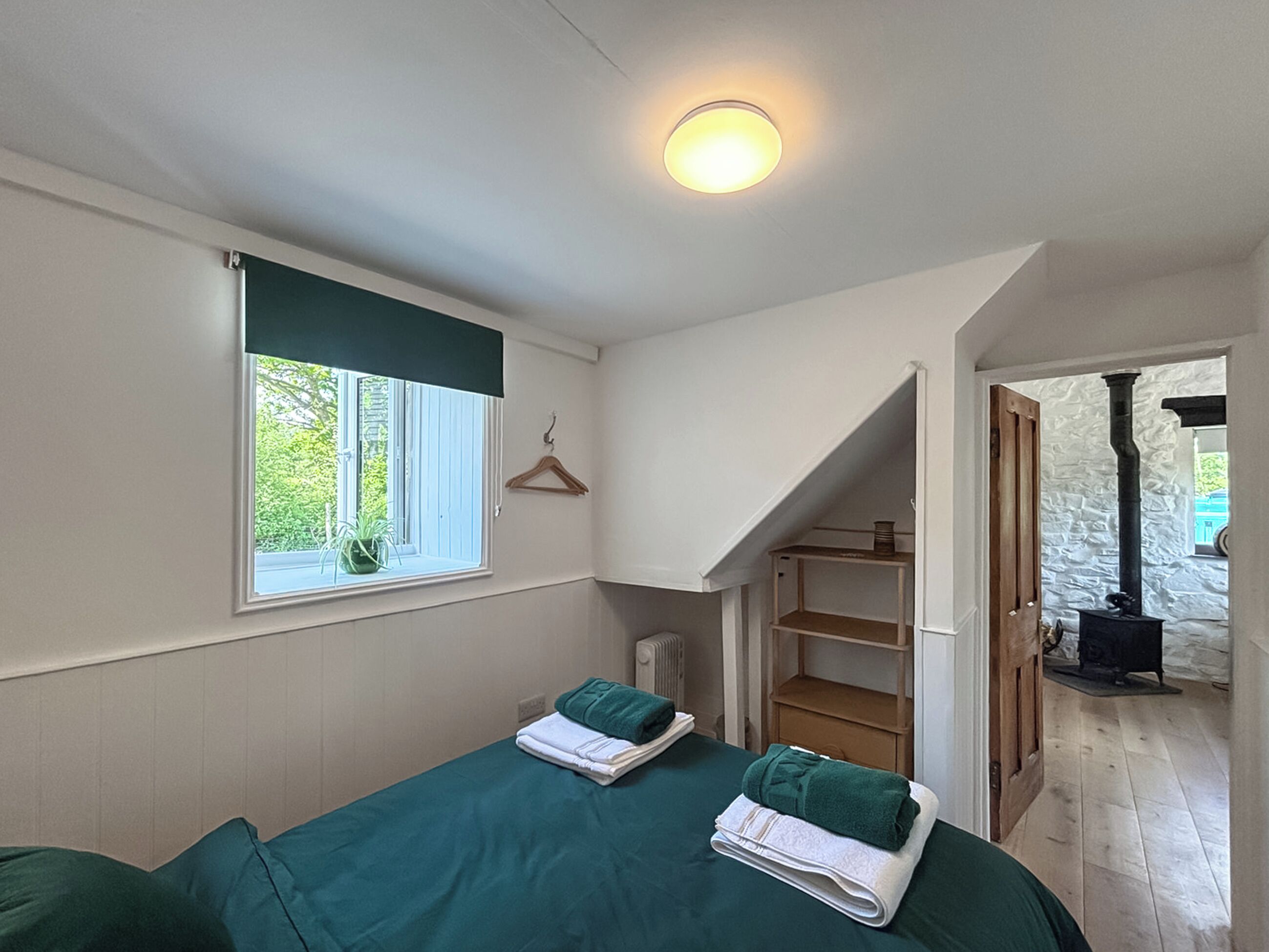 Un dormitorio con dos camas, una ventana con vistas, una puerta de madera y una pared de piedra.