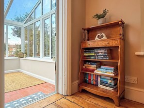 Una habitación con una estantería de madera, una puerta que da a un balcón y vistas a árboles.