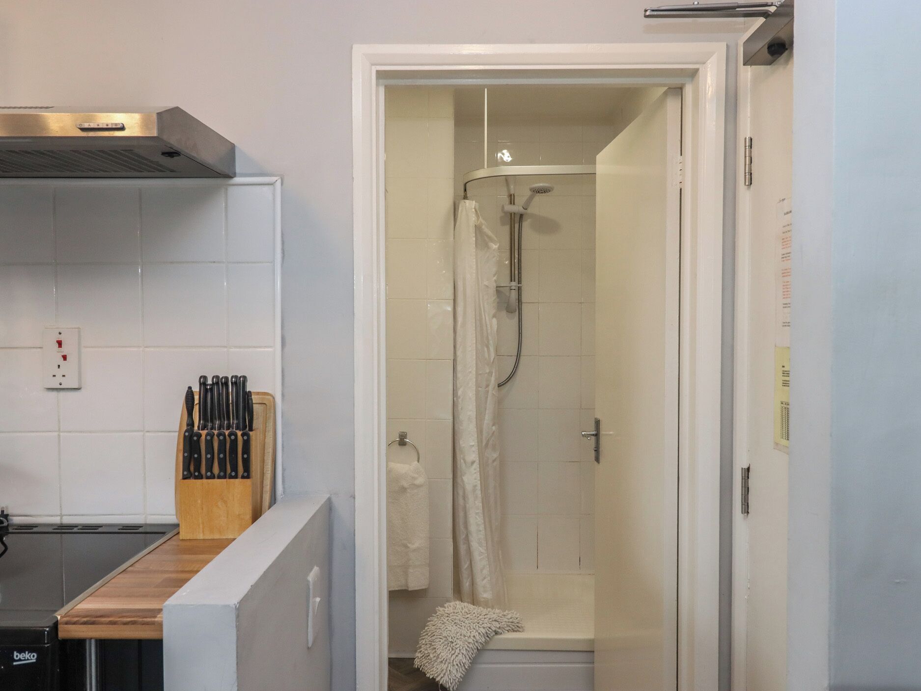 Un baño con ducha, una toalla y un juego de cuchillos en la encimera.