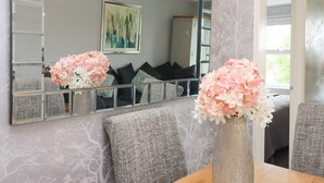 En modern inredning med en stor spegel, grå väggar med mönster och en matplats med en vas med blommor.