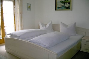 Ein Doppelbett mit weißer Bettwäsche, ein Nachttisch mit Schubladen und ein Gemälde an der Wand.