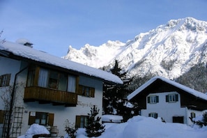 Ein mit Schnee bedeckter Berg mit einem Chalet im Vordergrund.