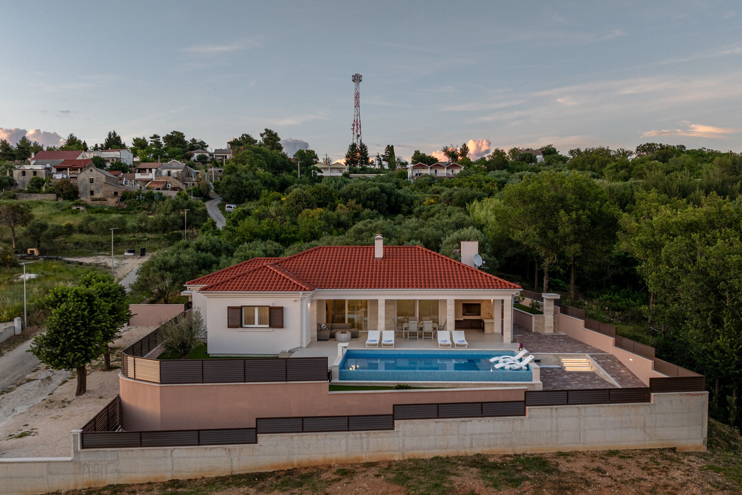 Una casa moderna con piscina, rodeada de vegetación y un cielo despejado.